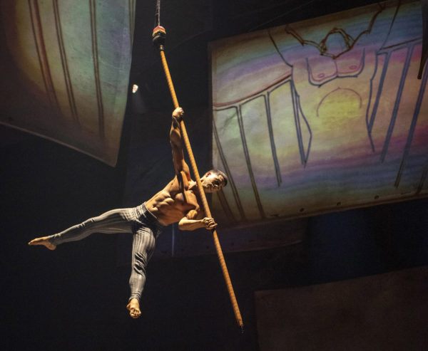 Celebrating the “pencil test,” an acrobat guides an aerial pole, stylized as a giant pencil, across the stage to create their own animation before propelling dramatically into the air during Drawn to Life, the highly anticipated new collaboration from Cirque du Soleil and Disney. The show premiered Nov. 18, 2021, at Walt Disney World Resort in Lake Buena Vista, Fla. (Kent Phillips, photographer). Photo credits (C) Disney Enterprises, Inc. All Rights Reserved 