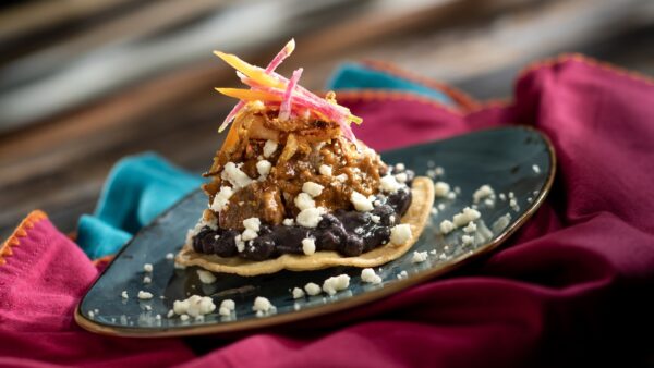 Tostada de Carne: Braised beef tips slowly cooked Mexican-style atop a fried corn tortilla with black beans, crispy onions, and queso fresco (New)