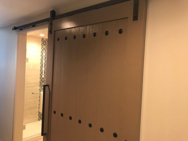 The bathroom is behind a trendy sliding barn door.