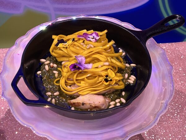 When Will My Life Begin Chicken and Pasta. Tangled egg yolk pasta, Forest moss and flowers, pine nut pesto, and braised chicken served in a frying pan. Available at Cinderella’s Royal Table