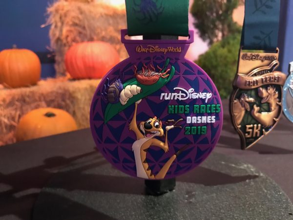 Timon serves up some grubs on this runDisney Kids Races Dashes "medal".